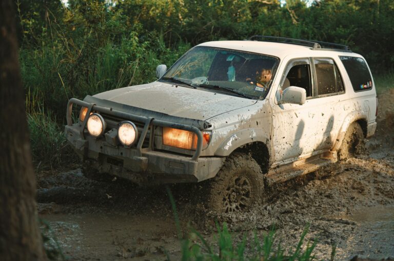 white 4 runner driving through mud