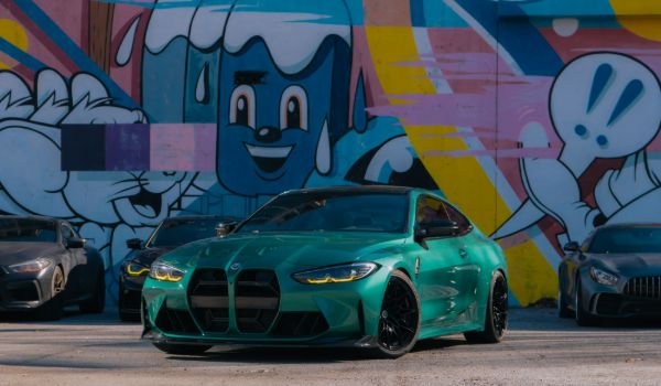 GREEN BMW PARKED BEHIND URBAN ART WALL
